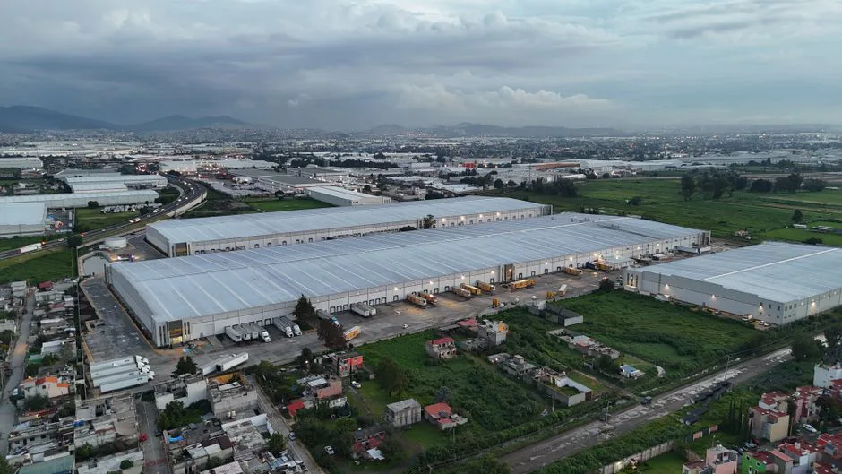 Caja de cartón con etiqueta de envío internacional y banderas de Estados Unidos y México sobre fondo de almacén