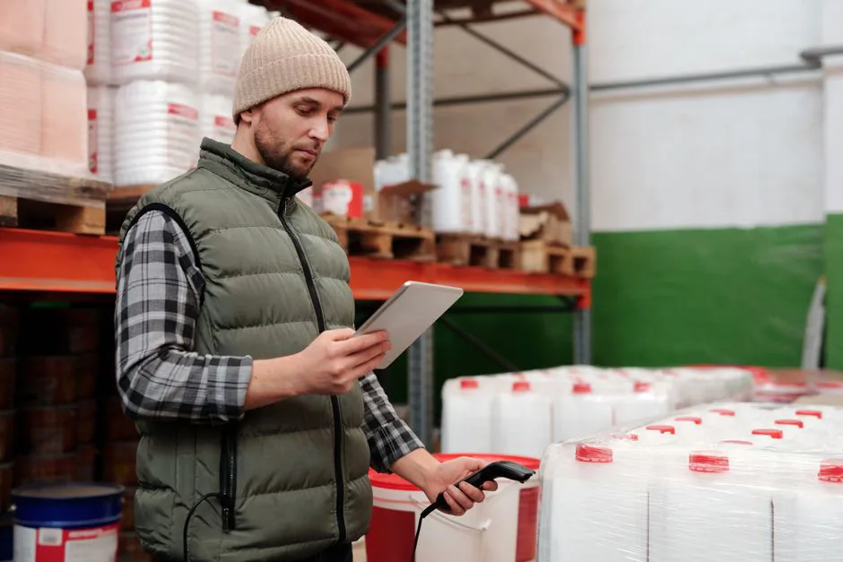 Warehouse worker scanning a package with a tablet, showing customs documents on screen